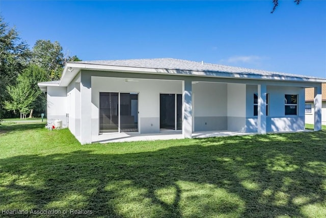 rear view of house featuring a lawn and a patio