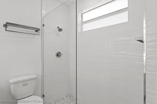 bathroom with a tile shower and toilet