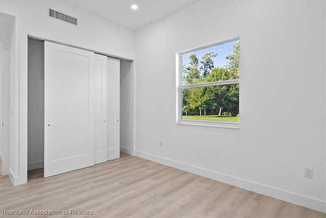 unfurnished bedroom with light wood-type flooring and a closet