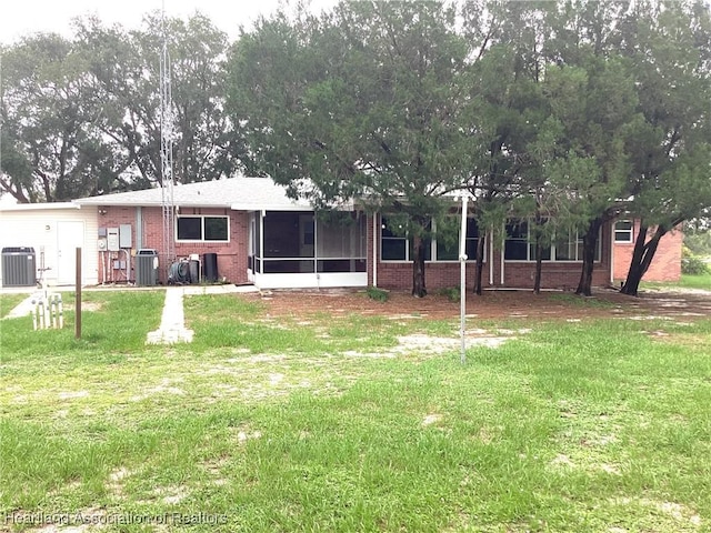 136 Hallmark Ave, Lake Placid, FL 33852 - rear view of house with brick siding, a sunroom, central AC unit, and a yard