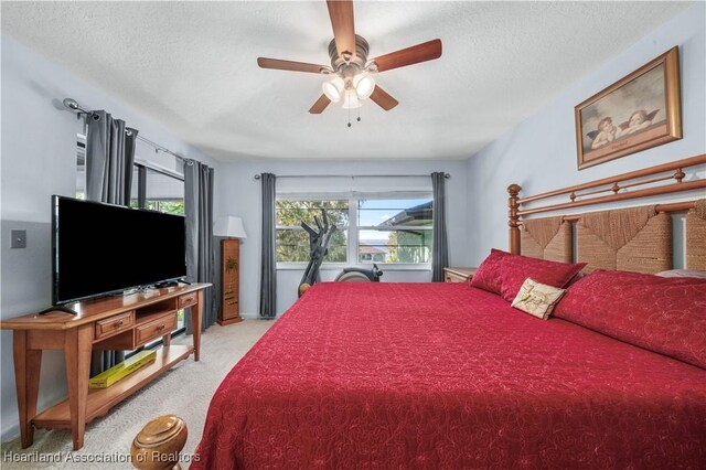 carpeted bedroom featuring a textured ceiling and ceiling fan