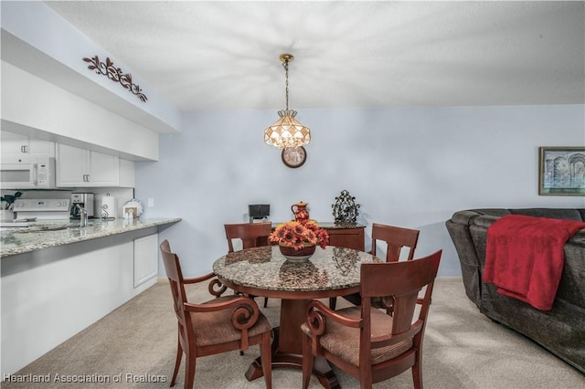 carpeted dining space with a chandelier