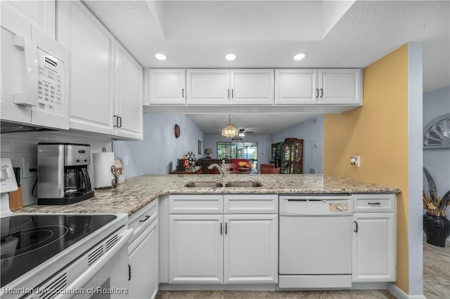 kitchen with white cabinetry, sink, light stone countertops, kitchen peninsula, and white appliances