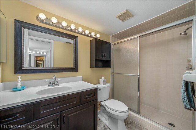 bathroom with vanity, toilet, and a shower with shower door