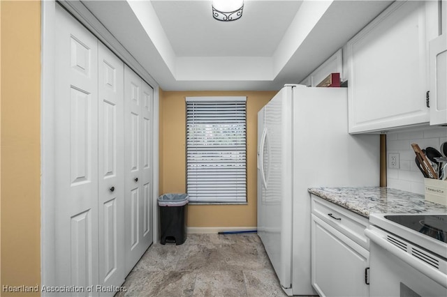 kitchen featuring tasteful backsplash, light stone counters, a raised ceiling, electric stove, and white cabinets