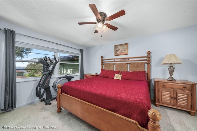 bedroom with a textured ceiling, light colored carpet, and ceiling fan