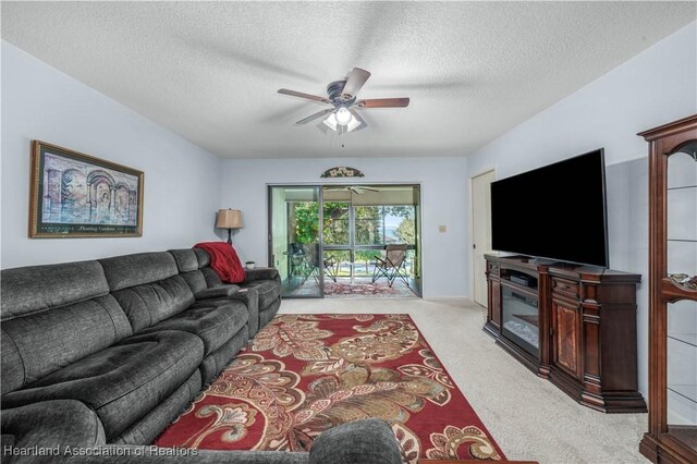 living room featuring ceiling fan, light carpet, and a textured ceiling