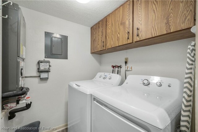 clothes washing area with cabinets, independent washer and dryer, a textured ceiling, and electric panel