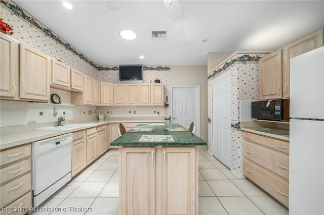 kitchen with light brown cabinets, a kitchen island, white appliances, and light tile patterned floors