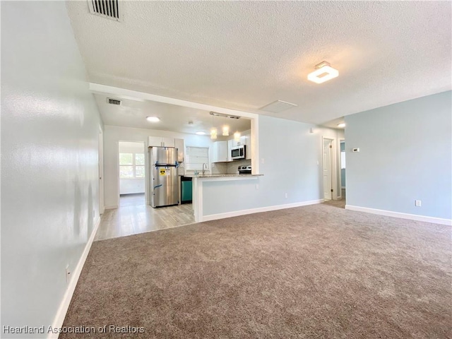 unfurnished living room featuring light colored carpet and a textured ceiling