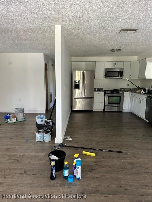 kitchen featuring dark wood finished floors, a textured ceiling, and stainless steel appliances