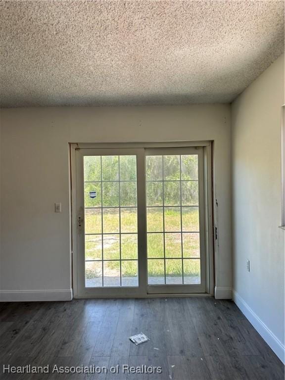 doorway with wood finished floors, a textured ceiling, and baseboards
