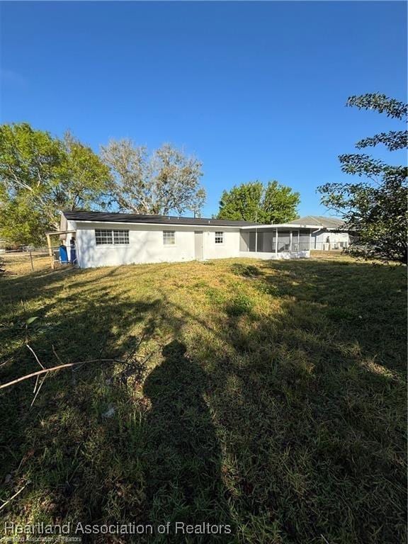 back of property featuring a yard, stucco siding, and a sunroom