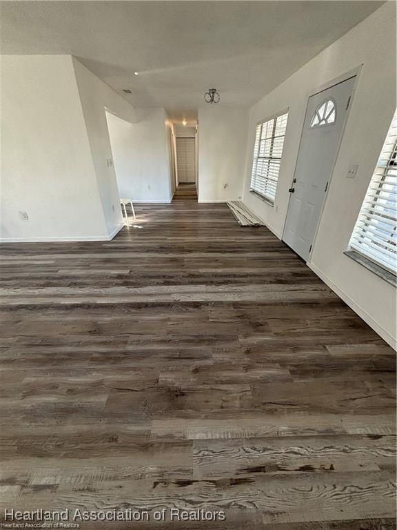 interior space featuring baseboards and dark wood-style floors