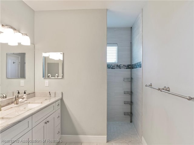 bathroom with tile patterned flooring, vanity, and a tile shower