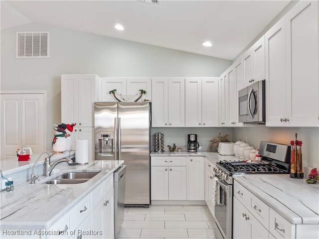 kitchen featuring appliances with stainless steel finishes, white cabinetry, lofted ceiling, and sink