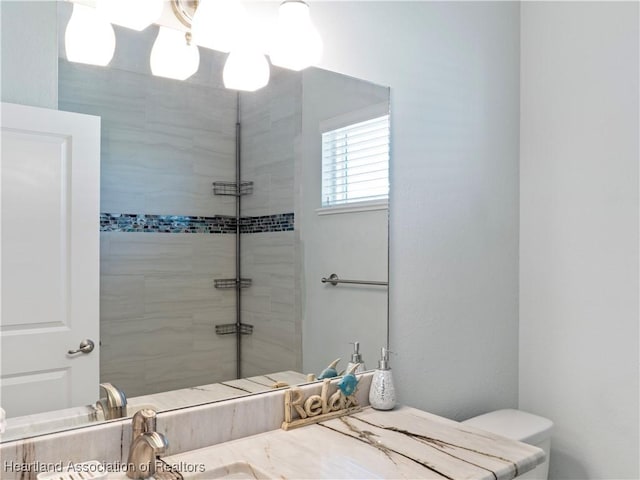 bathroom with a tile shower and vanity