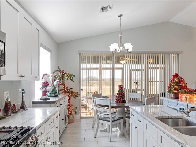 kitchen featuring white cabinetry, light stone countertops, lofted ceiling, and a notable chandelier