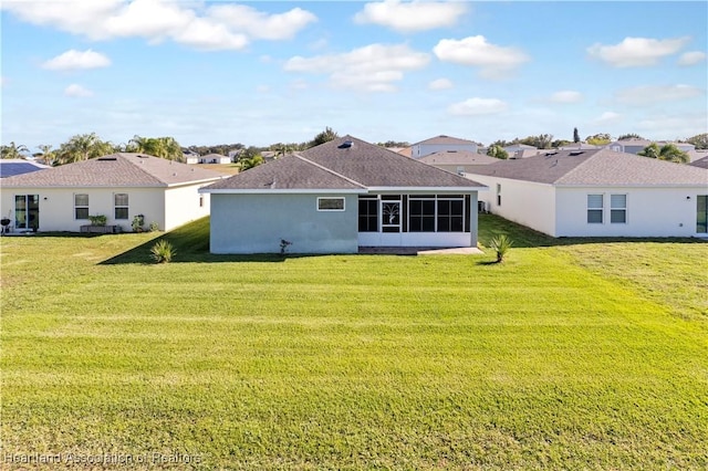 rear view of house featuring a sunroom and a yard