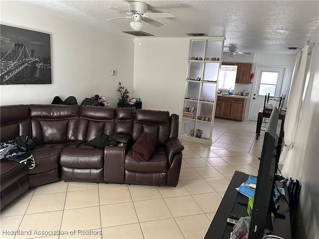 tiled living room featuring ceiling fan and a textured ceiling