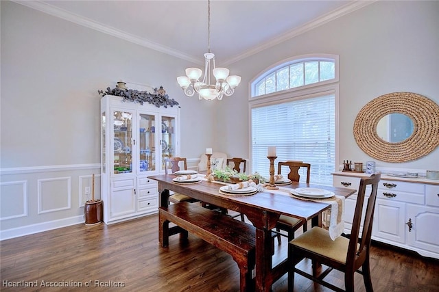 dining room featuring dark wood-style flooring, crown molding, a decorative wall, an inviting chandelier, and wainscoting