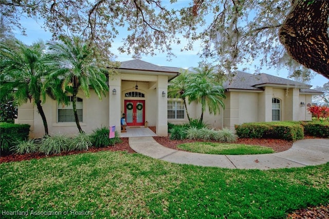 view of front of property featuring stucco siding, a shingled roof, french doors, and a front yard