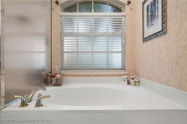 bathroom featuring a tub to relax in and a wealth of natural light