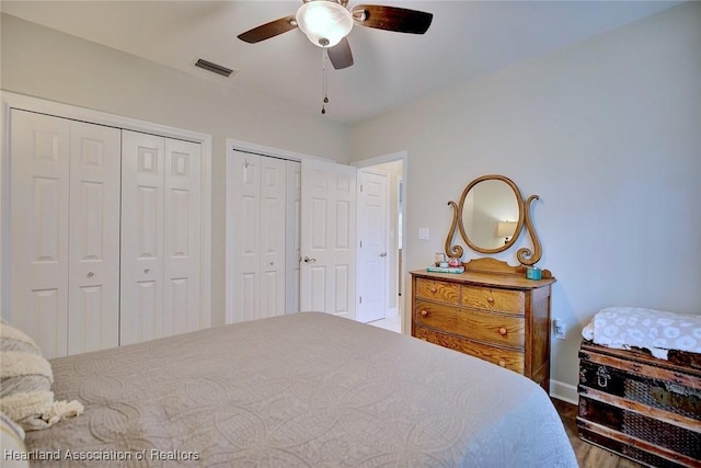 bedroom with a ceiling fan, visible vents, and multiple closets