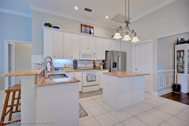 kitchen featuring pendant lighting, crown molding, a sink, white appliances, and a peninsula