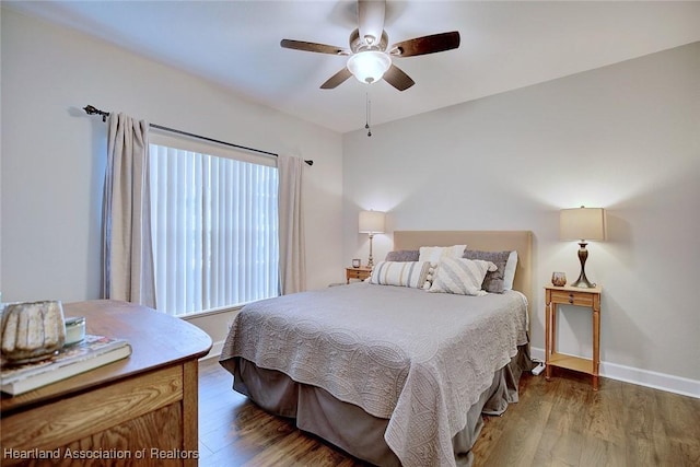 bedroom with ceiling fan, baseboards, and dark wood-type flooring