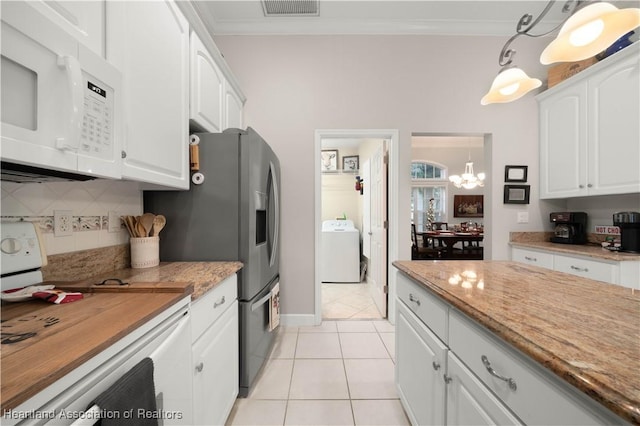 kitchen with white cabinetry, decorative light fixtures, white appliances, and washer / dryer