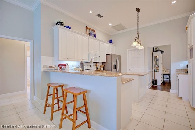 kitchen with light stone counters, visible vents, white microwave, white cabinetry, and stainless steel fridge