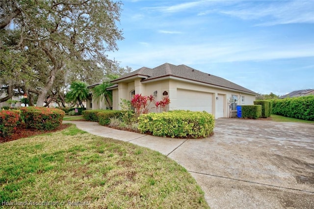 view of front of house featuring an attached garage, driveway, a front yard, and stucco siding