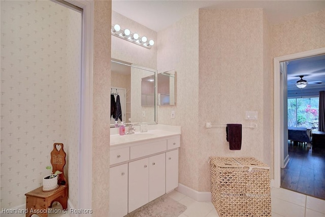 full bathroom featuring ceiling fan, vanity, tile patterned flooring, baseboards, and wallpapered walls