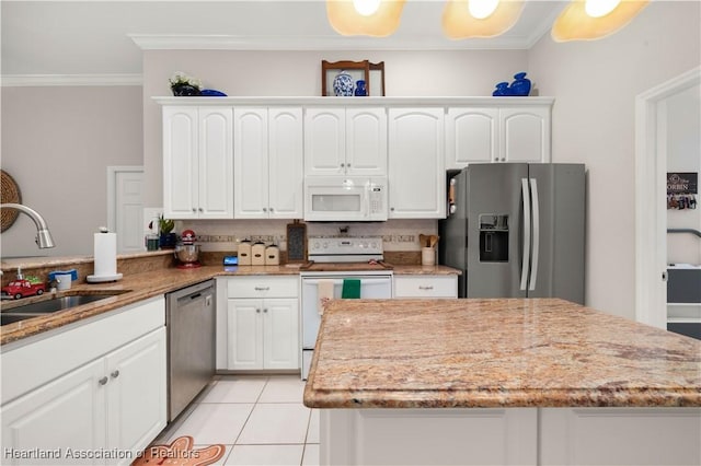 kitchen with light stone countertops, appliances with stainless steel finishes, crown molding, sink, and white cabinetry