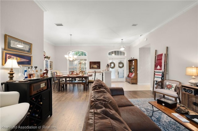 living room with crown molding, a notable chandelier, and light wood-type flooring