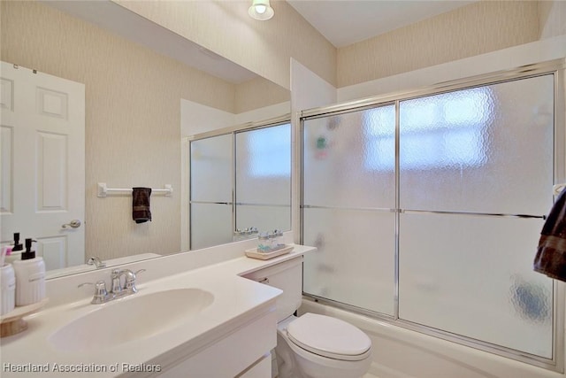 bathroom featuring enclosed tub / shower combo, toilet, and vanity