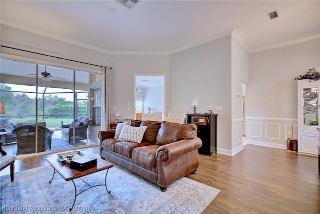 living area featuring ornamental molding, visible vents, ceiling fan, and wood finished floors