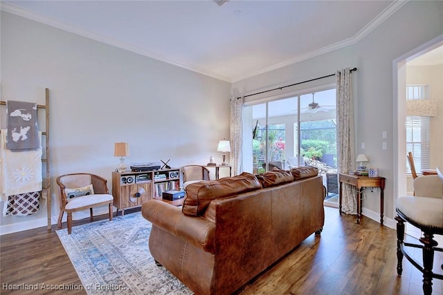 living room featuring dark wood-type flooring, ornamental molding, and baseboards