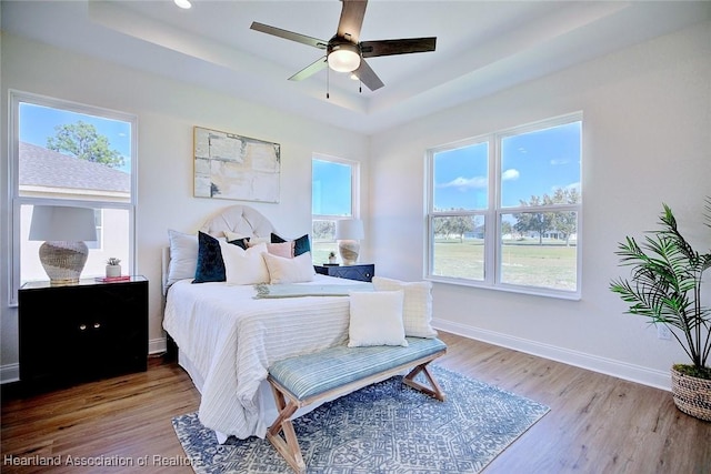 bedroom featuring ceiling fan, hardwood / wood-style floors, and a tray ceiling