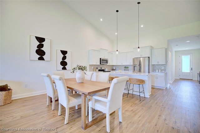 dining room featuring light hardwood / wood-style flooring and high vaulted ceiling