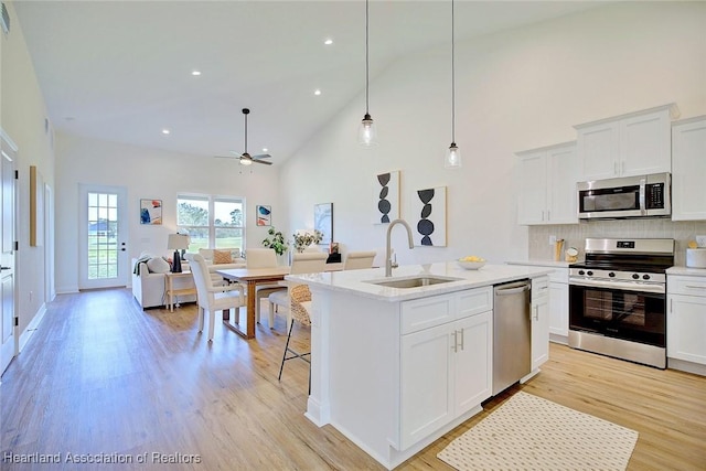 kitchen with sink, stainless steel appliances, white cabinetry, and a center island with sink