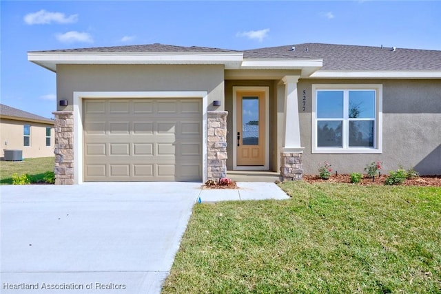 view of front of property with a front yard, central AC unit, and a garage