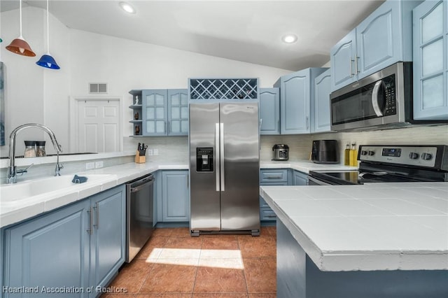 kitchen featuring a sink, visible vents, appliances with stainless steel finishes, tile counters, and open shelves