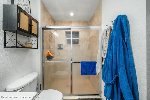 bathroom featuring a textured wall, a shower stall, and toilet