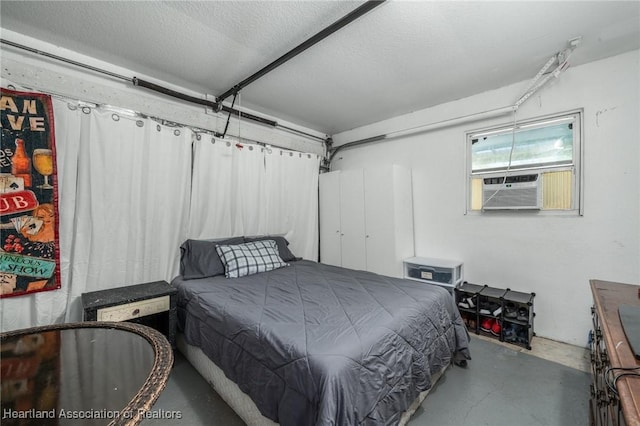 bedroom with concrete flooring, a textured ceiling, cooling unit, and a garage