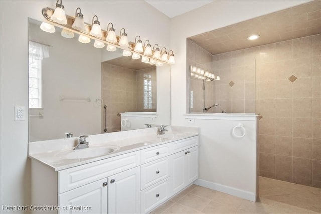 bathroom with tile patterned flooring, vanity, and tiled shower