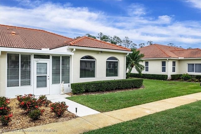 mediterranean / spanish-style house featuring a front lawn and a sunroom