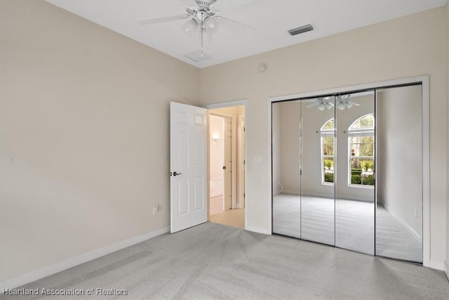 unfurnished bedroom featuring light colored carpet, a closet, and ceiling fan