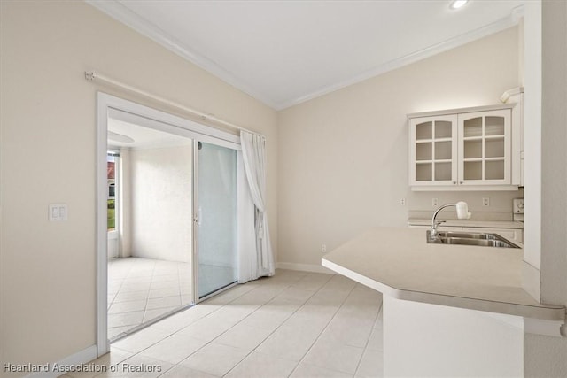 kitchen featuring light tile patterned floors, white cabinetry, ornamental molding, and sink